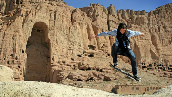 Foto de chica afgana saltando con monopatín