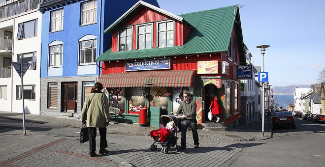 Imagen de un hombre llevando un carrito de bebé en una calle islandesa con 