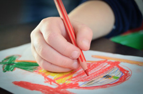 Imagen de la mano de un niño o niña dibujando