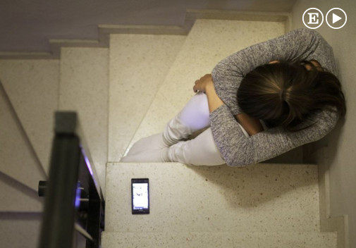 Imagen de una joven en una escalera con un móvil en el suelo