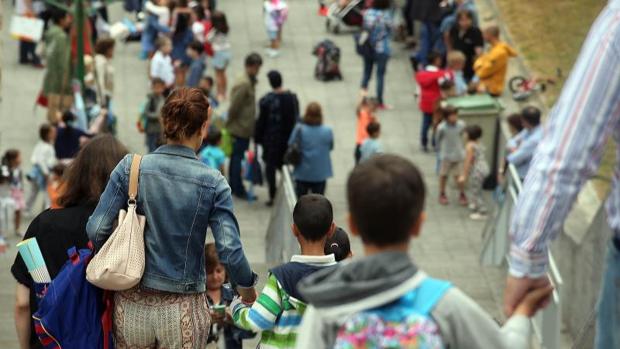 Imagen de un grupo de padres y niños llegando a un colegio