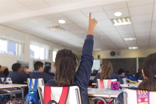 una niña levanta la mano en clase
