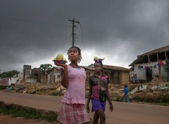 Imagen de dos mujeres comerciando ante unas ruinas en Liberia