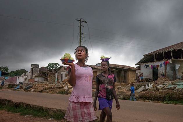 Imagen de dos mujeres comerciando ante unas ruinas en Liberia