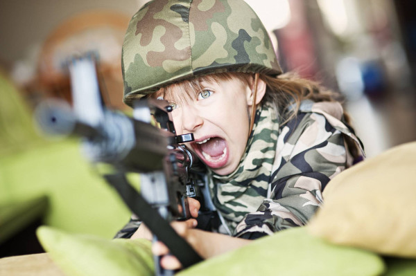 una niña vestida de soldado y con un arma y cara muy agresiva