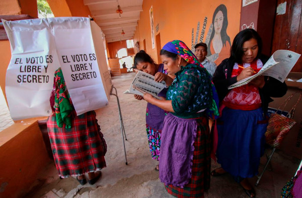 un grupo de mujeres indígenas en una mesa electoral