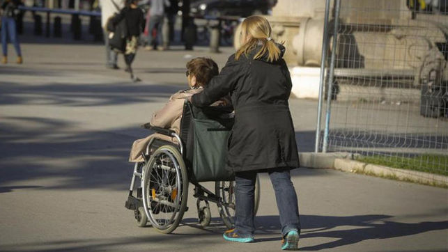 una mujer empuja una silla de ruedas