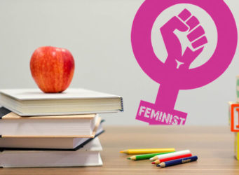 libros sobre una mesa y una manzana con un símbolo feminista