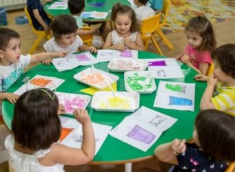 varios nenes y nenas en una mesa pintando