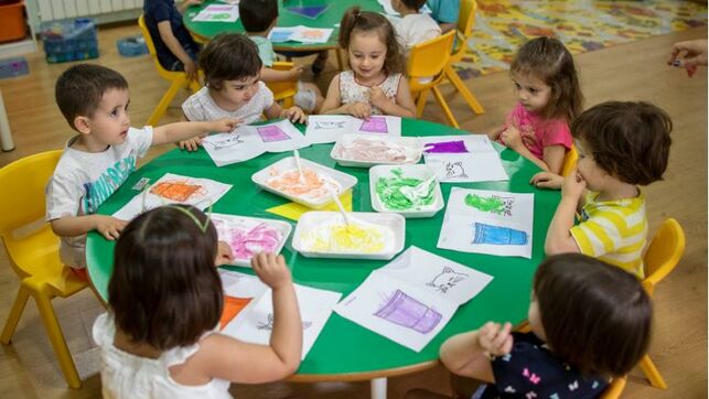 varios nenes y nenas en una mesa pintando