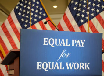 Imagen del cartel igual paga por igual trabajo en inglés delante de la bandera de USA
