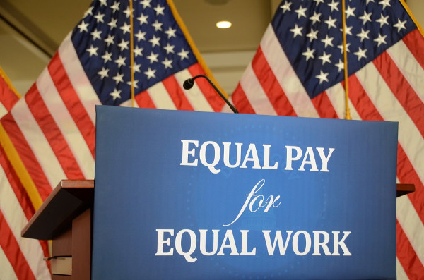 Imagen del cartel igual paga por igual trabajo en inglés delante de la bandera de USA