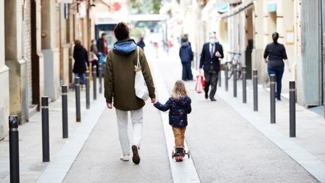 un niño y un adulto pasean por la calle 