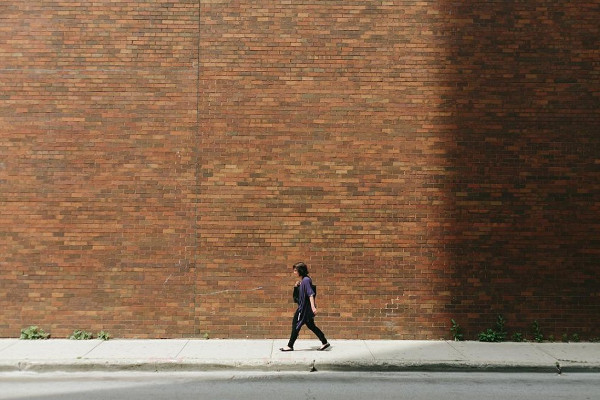 una mujer camina delante de un muro de ladrillo