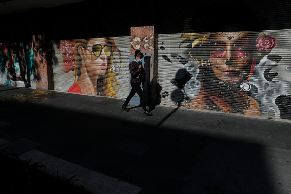 una mujer pasa ante dos murales de mujeres