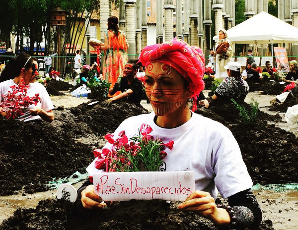 una joven con la cara pintada y una planta en sus manos