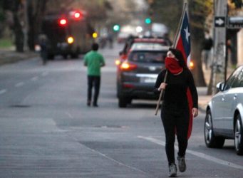 una mujer chilena con la cara tapada y una bandera