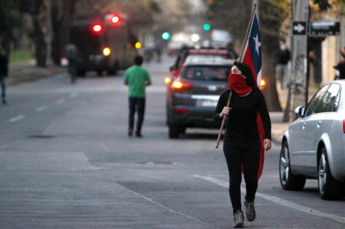 una mujer chilena con la cara parcialmente tapada y una bandera