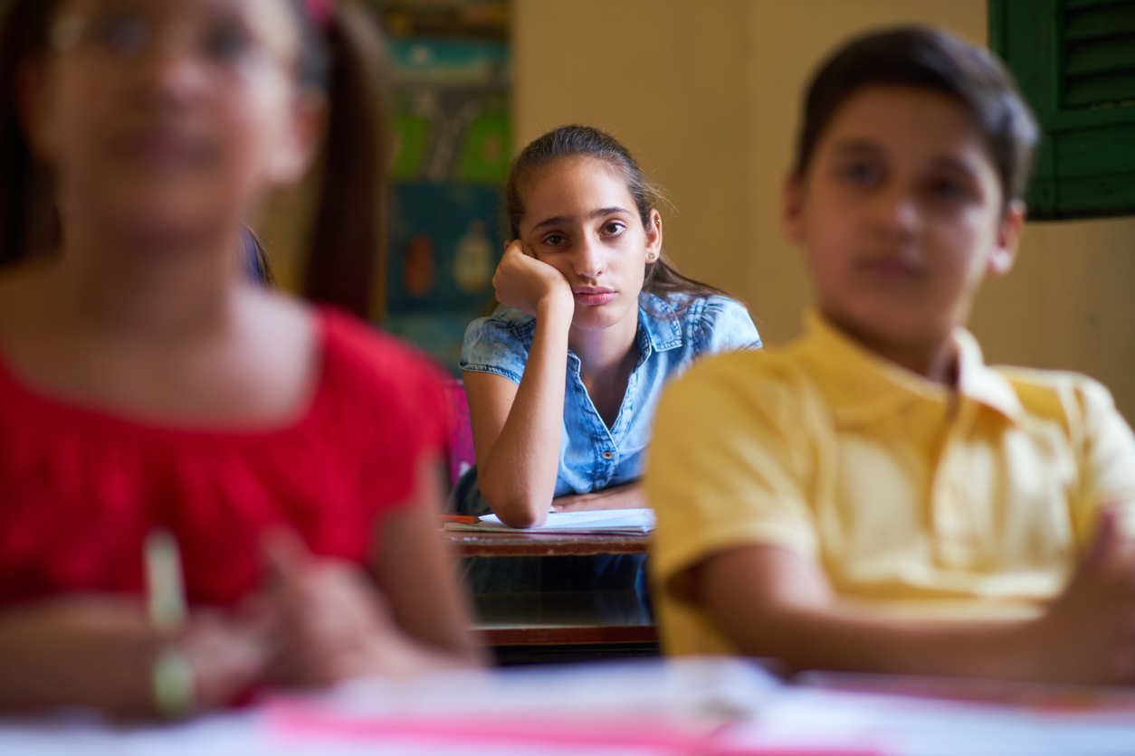 imagen de una niña en una clase con cara de aburrida