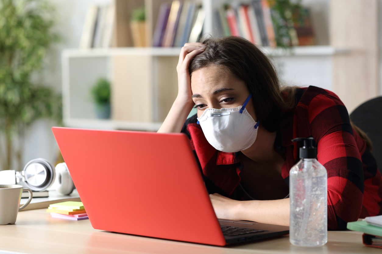 una joven con mascarilla ante un ordenador