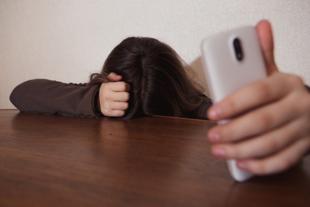 una joven con el teléfono en la mano mira al suelo