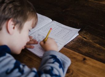 un niño escribe en un cuadernillo