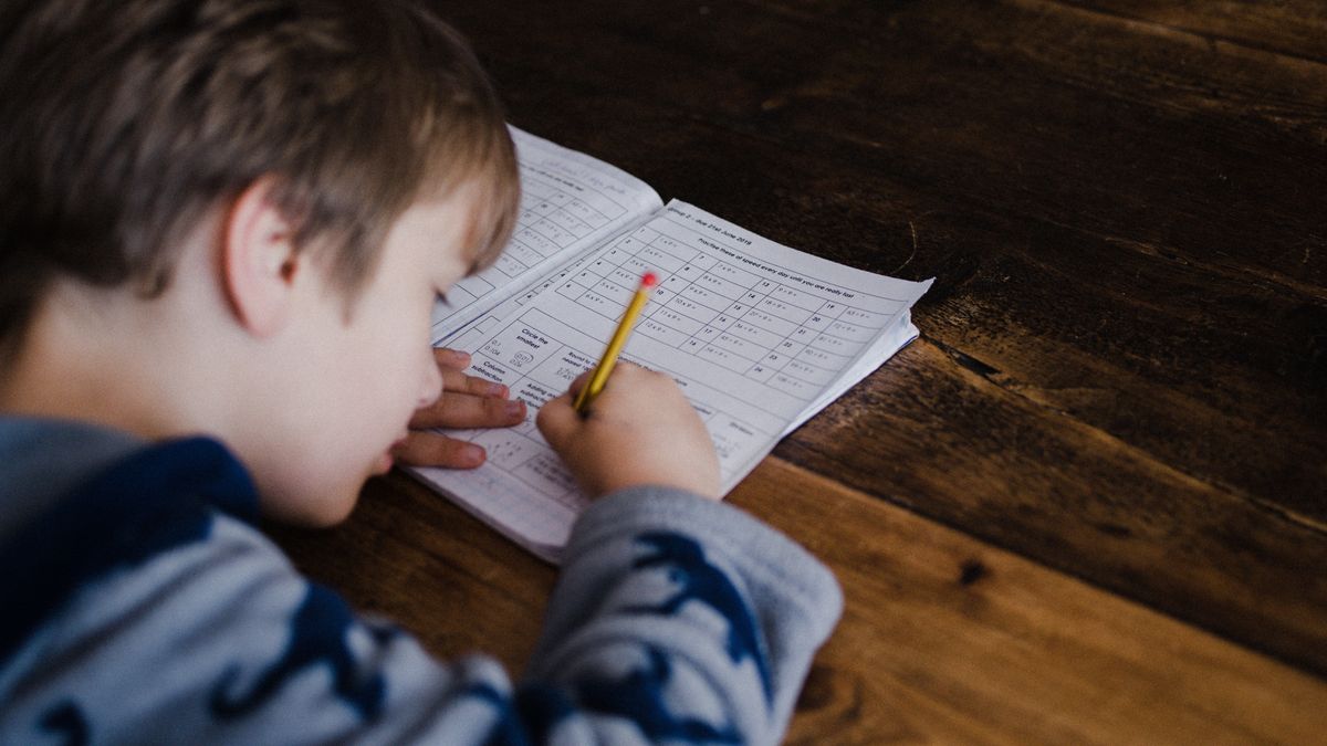 un niño escribe en un cuadernillo