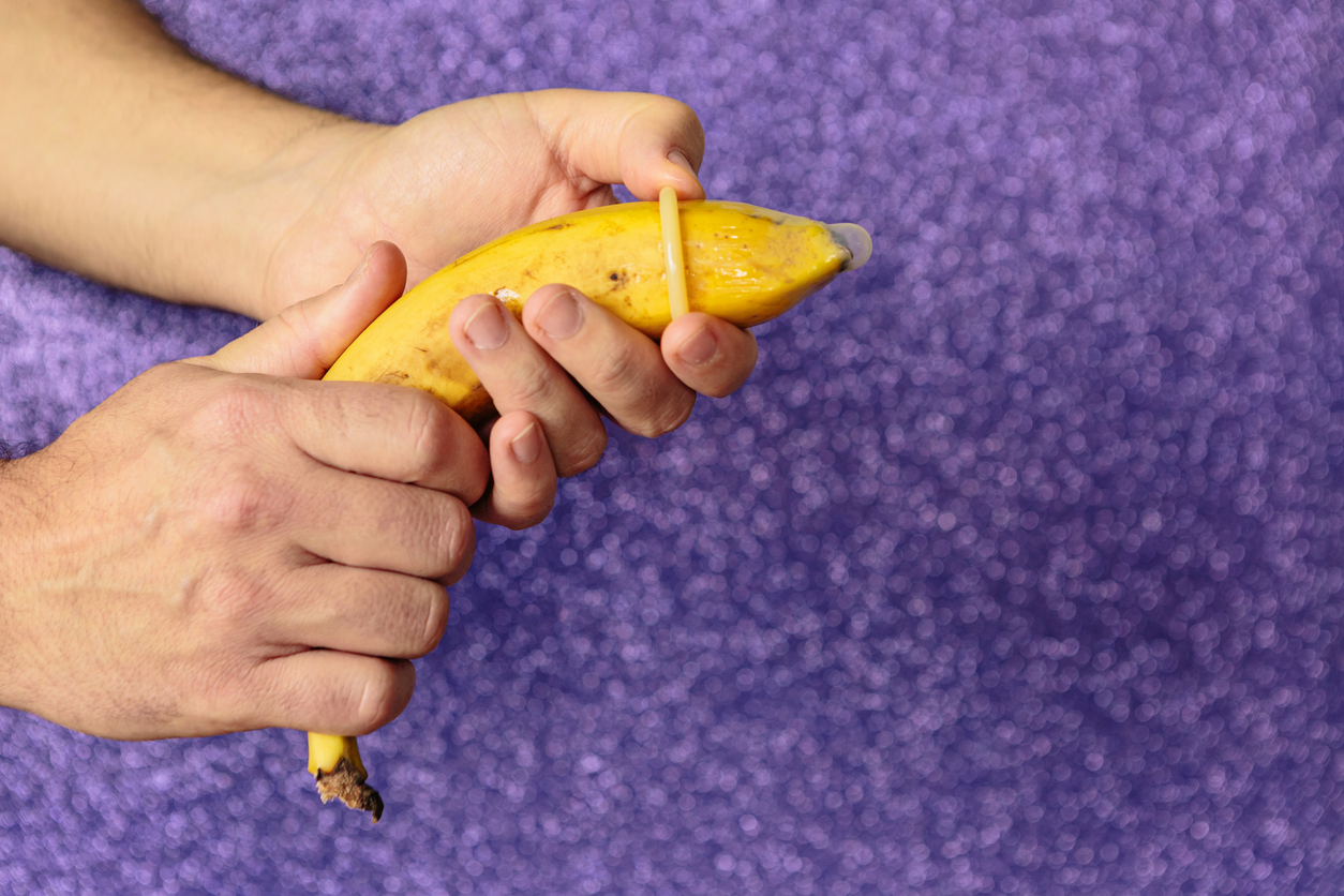 una mano pone un preservativo a una banana