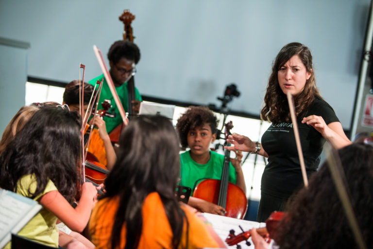 grupo de niños y niñas con instrumentos musicales y una profesora