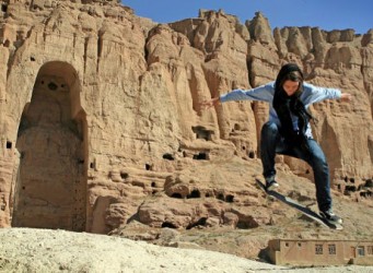 Foto de chica afgana saltando con monopatín