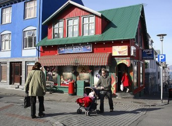 Imagen de un hombre llevando un carrito de bebé en una calle islandesa con