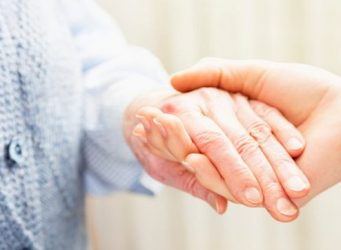 Imagen de las manos de una persona mayor y su cuidadora
