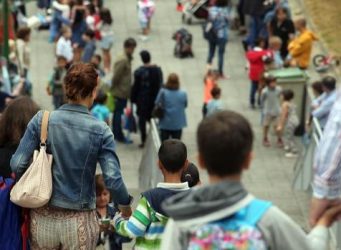 Imagen de un grupo de padres y niños llegando a un colegio