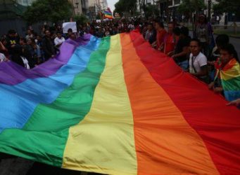 Personas sujetando una bandera LGTBI
