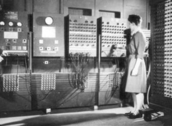 Imagen antigua de dos mujeres ante un enorme ordenador. La de la izquierda es Bartik