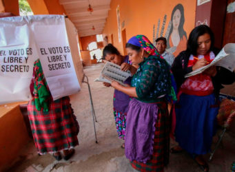 un grupo de mujeres indígenas en una mesa electoral