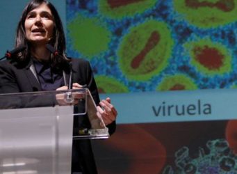 imagen de una científica delante de una diapositiva del virus de la viruela