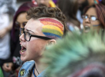 Imagen de una persona con la bandera arcoiris pintada en la cabeza