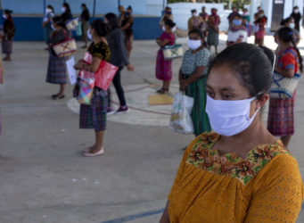 mujeres con mascarilla y manteniendo distancia en un patio