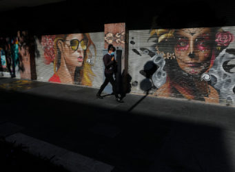 una mujer pasa ante dos murales de mujeres