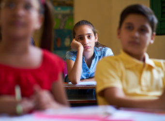 imagen de una niña en una clase con cara de aburrida