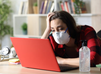 una joven con mascarilla ante un ordenador