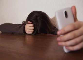 una joven con el teléfono en la mano mira al suelo