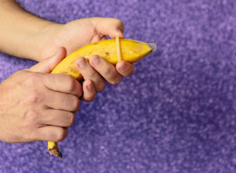 una mano pone un preservativo a una banana