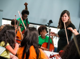 grupo de niños y niñas con instrumentos musicales y una profesora